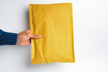 Male hand holding parcel post against white background