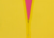 Yellow zipper unzipped half way showing violet color under a yellow background.
