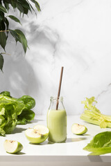 Wall Mural - Green detox smoothies in a bottle standing on white table, front view