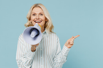 Wall Mural - Elderly smiling woman 50s wear striped shirt hold scream in megaphone announces discounts sale Hurry up point finger aside on workspace isolated on plain pastel light blue color background studio