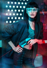 Cyberpunk Girl In Futuristic Glasses With A Blaster In Her Hand In The City Of The Future.