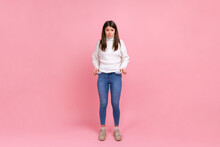 Full Length Portrait Of Girl Showing Empty Pockets And Looking Frustrated About Loans And Debts, Wearing White Casual Style Sweater. Indoor Studio Shot Isolated On Pink Background.