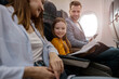 © Friends Stock - Joyful little girl traveling with parents on airplane