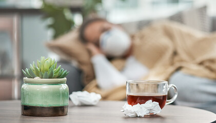 Wall Mural - On the road to recovery. Shot of dirty tissues and a cup of tea on a table next to a woman lying sick at home.