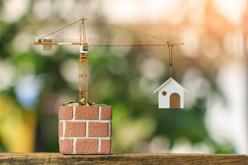 Flower pot and gold coins with growing and tower crane with build new house put on the green grass in the public park, saving money or loan for construction real estate and home concept.