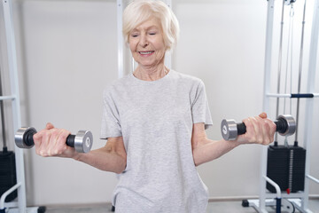 Wall Mural - Female lifting dumbbells with both hands and smiling