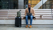 Business man with suitcase sitting on bench using laptop