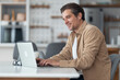 © Jelena - Side view of a middle-aged freelancer typing on a laptop keyboard answering emails.