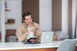 © Jelena - Middle-aged man taking notes while watching online course on laptop.
