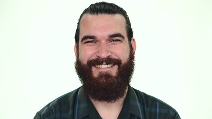 Wall Mural - Close up footage of young bearded man smiling at the camera over white background.