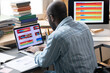 © AnnaStills - Rear view of African engineer sitting at his workplace with laptop and typing, he examining graphs on the screen