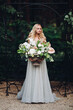 Young elegant beutiful blondy bride holding in hand wedding boquet.