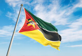 Fototapeta  - Mozambique flag waving in the wind on flagpole. Mozambique flag waving a blue cloudy sky
