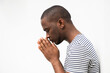 Profile of african american man praying with hands clasp by isolated white background
