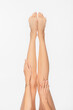 © LIGHTFIELD STUDIOS - cropped view of barefoot woman with tattooed arm and slender legs isolated on white