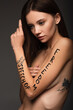 © LIGHTFIELD STUDIOS - young brunette woman with freedom of speech lettering on arm isolated on dark grey