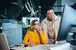 © Liubomir - Two freelancers, an Asian man and a woman, work in a modern office, discussing and discussing a joint project, looking at a computer monitor
