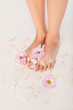 © LIGHTFIELD STUDIOS - cropped view of young woman with chrysanthemum flowers and petals near feet on white background