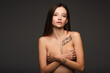 © LIGHTFIELD STUDIOS - nude woman with gender equality lettering on body hiding breast under hands isolated on dark grey
