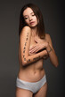 © LIGHTFIELD STUDIOS - slim woman with speak your mind lettering on body covering breast with hands isolated on dark grey