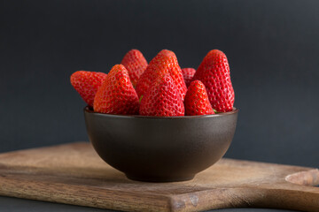 Wall Mural - bowl with strawberries on wooden board and on black background