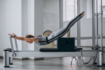 Woman practising pilates in a pilates reformer