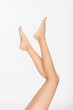 © LIGHTFIELD STUDIOS - partial view of barefoot and slender female legs isolated on white