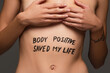 © LIGHTFIELD STUDIOS - cropped view of nude woman with body positive saved my life inscription on body isolated on dark grey