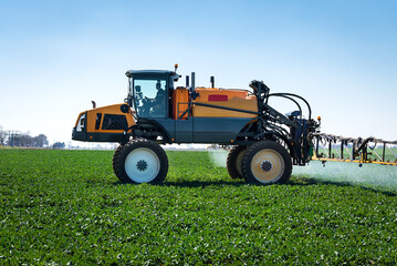 Aufkleber - Aerial image of tractor spraying soil and young crop in springtime in field.