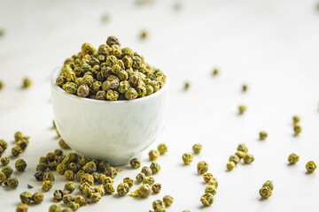 Poster - Dried green peppercorn. Dry green pepper spice in bowl on white table.