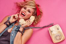 Everyone Had So Much Fun In The 80s. Studio Shot Of A Young Woman Holding A Telephone While Wearing 80s Clothing.