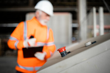 Wall Mural - Industrial machines equipment and emergency stop switch. In background employee working.