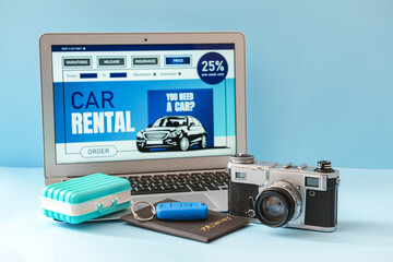 Wall Mural - Laptop with open page of car rental site, toy suitcase, key, passport and photo camera on color background