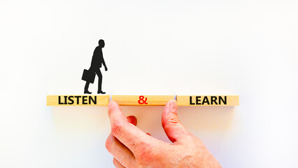 Poster - Listen and learn symbol. Concept words Listen and learn on wooden blocks. Beautiful white table white background. Businessman hand. Copy space. Business, educational and listen and learn concept.