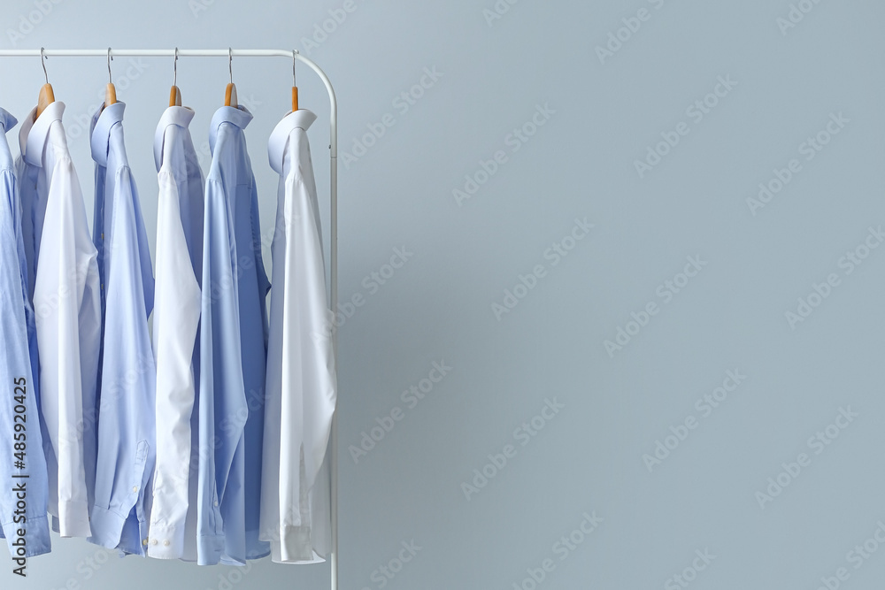 Rack with clean shirts on grey background