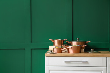 Cooking pots with prepared food on wooden table near color wall