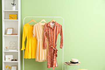 Wall Mural - Hanger with dresses and shelf unit with accessories near color wall