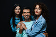 Man and two beautiful women on dark background. Polyamory concept