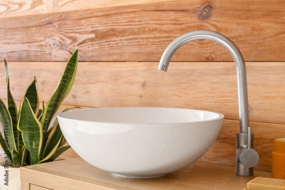 White sink with silver faucet near wooden wall
