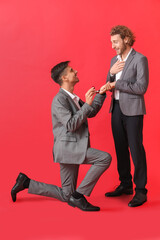 Canvas Print - Young gay proposing to his boyfriend on red background