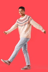 Wall Mural - Handsome African-American guy in knitted sweater on red background