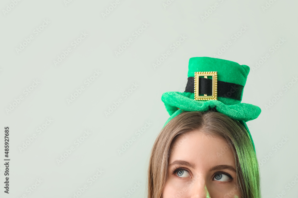 Young woman in green hat on light background, closeup. St. Patrick's Day celebration