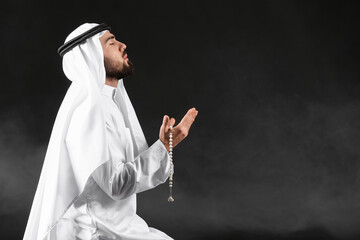 Wall Mural - Praying young Muslim man on dark background