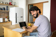© Buonaventura - Young business man working at home in his kitchen with laptop and papers on kitchen wooden desk. Home office concept.