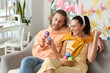 © Pixel-Shot - Young couple breaking Easter eggs on sofa at home