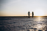 Fototapeta  - couple walking on the beach at sunset love sun man woman sunset 