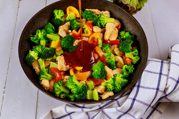 Wall Mural - Spicy chicken with broccoli in pan on white background.