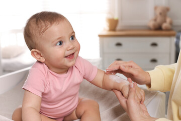 Sticker - Mother applying body cream on her little baby at home, closeup