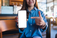 Mockup Image Of A Young Woman Holding, Showing And Pointing Finger At A Mobile Phone With Blank White Screen