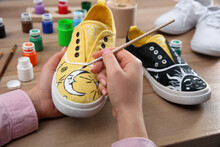 Woman Painting On Sneaker At Wooden Table, Closeup. Customized Shoes